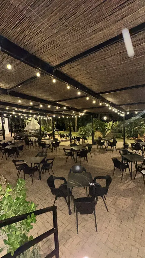 Terrasse bei Nacht unter dem Schilfdach mit leuchtenden Lichterketten